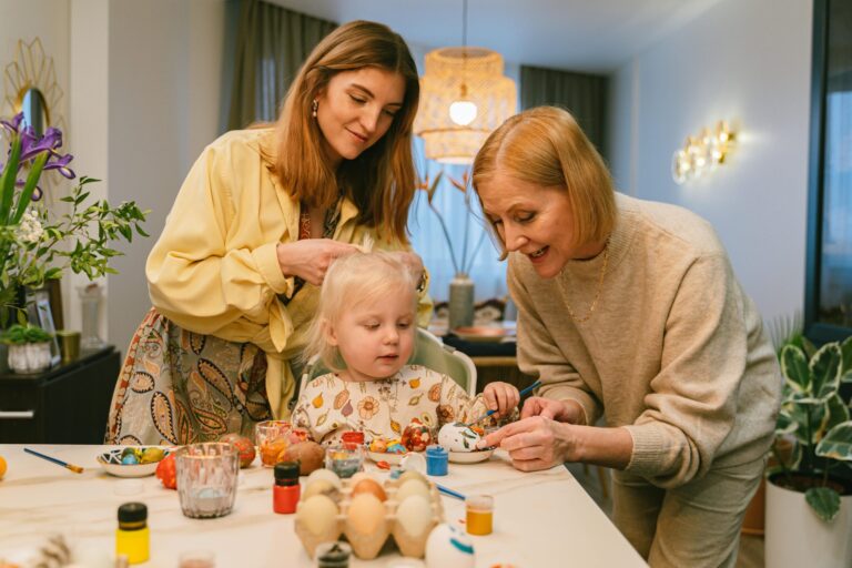 Mother, grandmother, and child painting Easter eggs together at home – fun spring activities for kids, creative crafts, and family bonding.