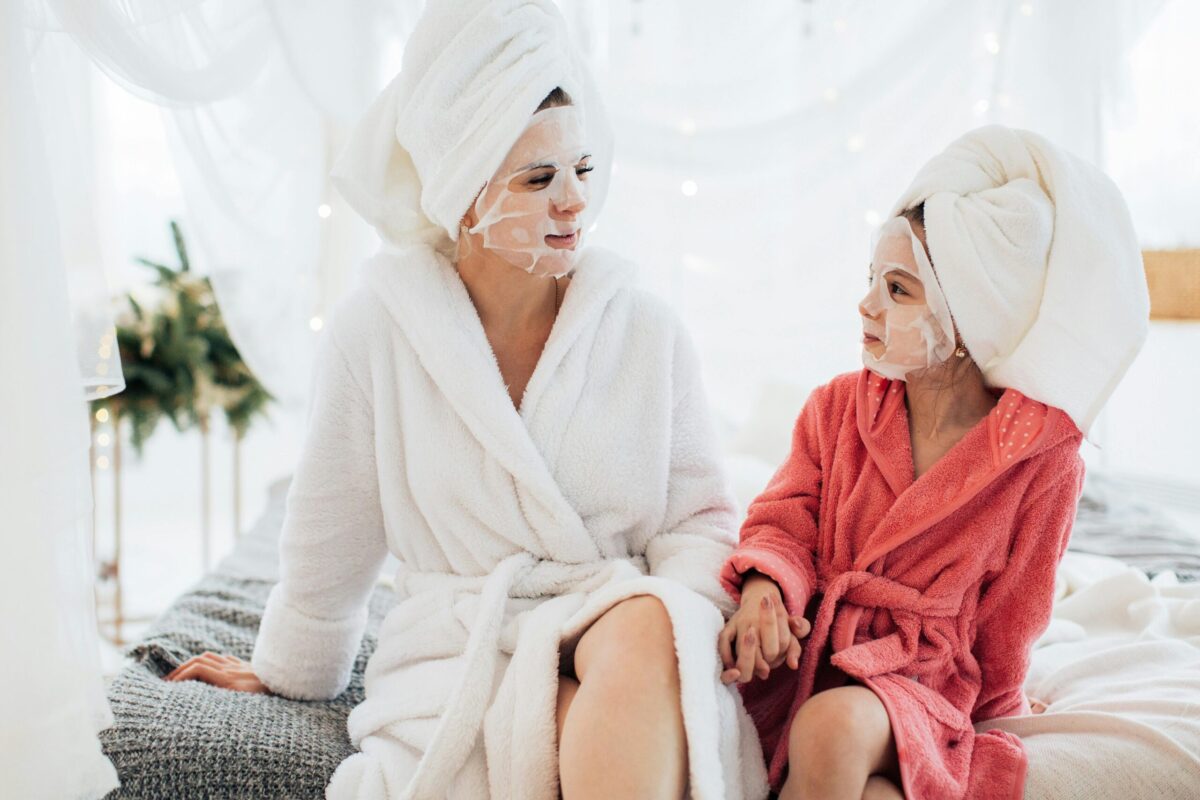Single mum and child enjoying affordable self-care rituals with face masks at home.